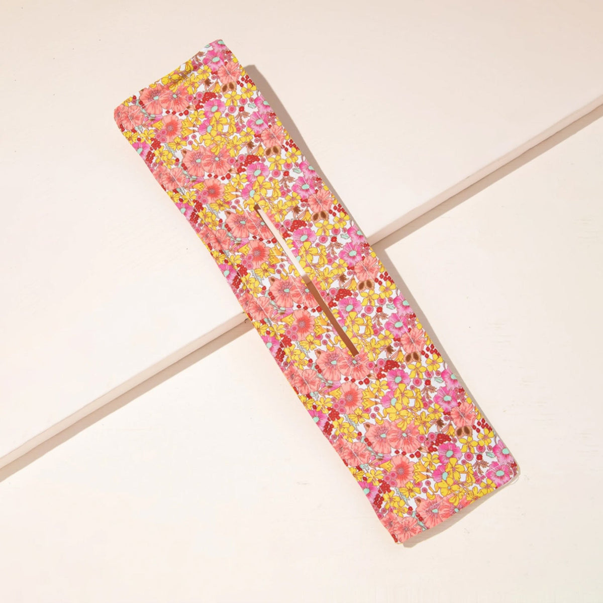 Pink and yellow knotted wire headband with a metal wire visible through the central opening.