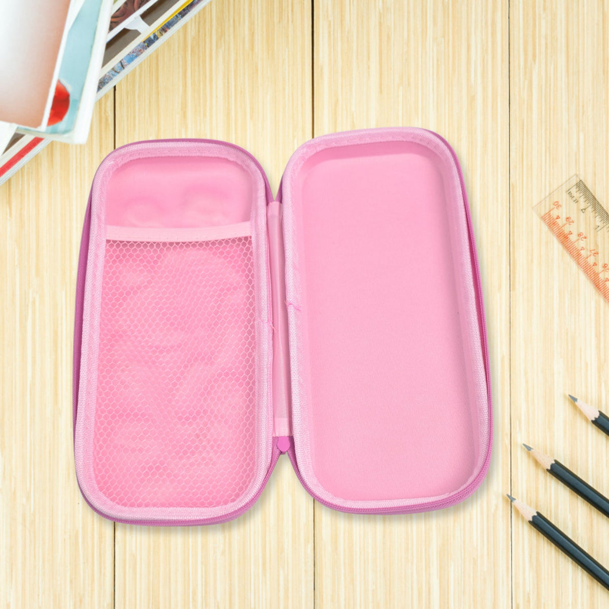The open pink interior of a mermaid pencil case, showing a mesh pocket on one side, on a light wooden surface with pencils.