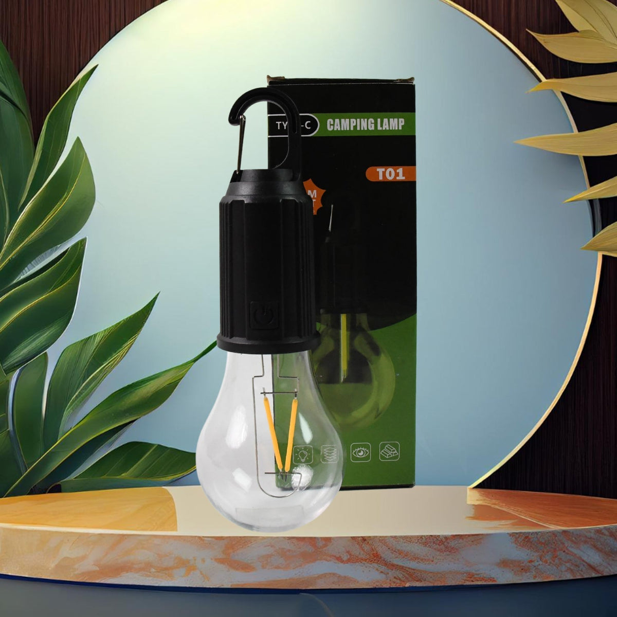 A clear LED bulb with a black top and hook stands on a marble pedestal, with its green and black packaging behind it.