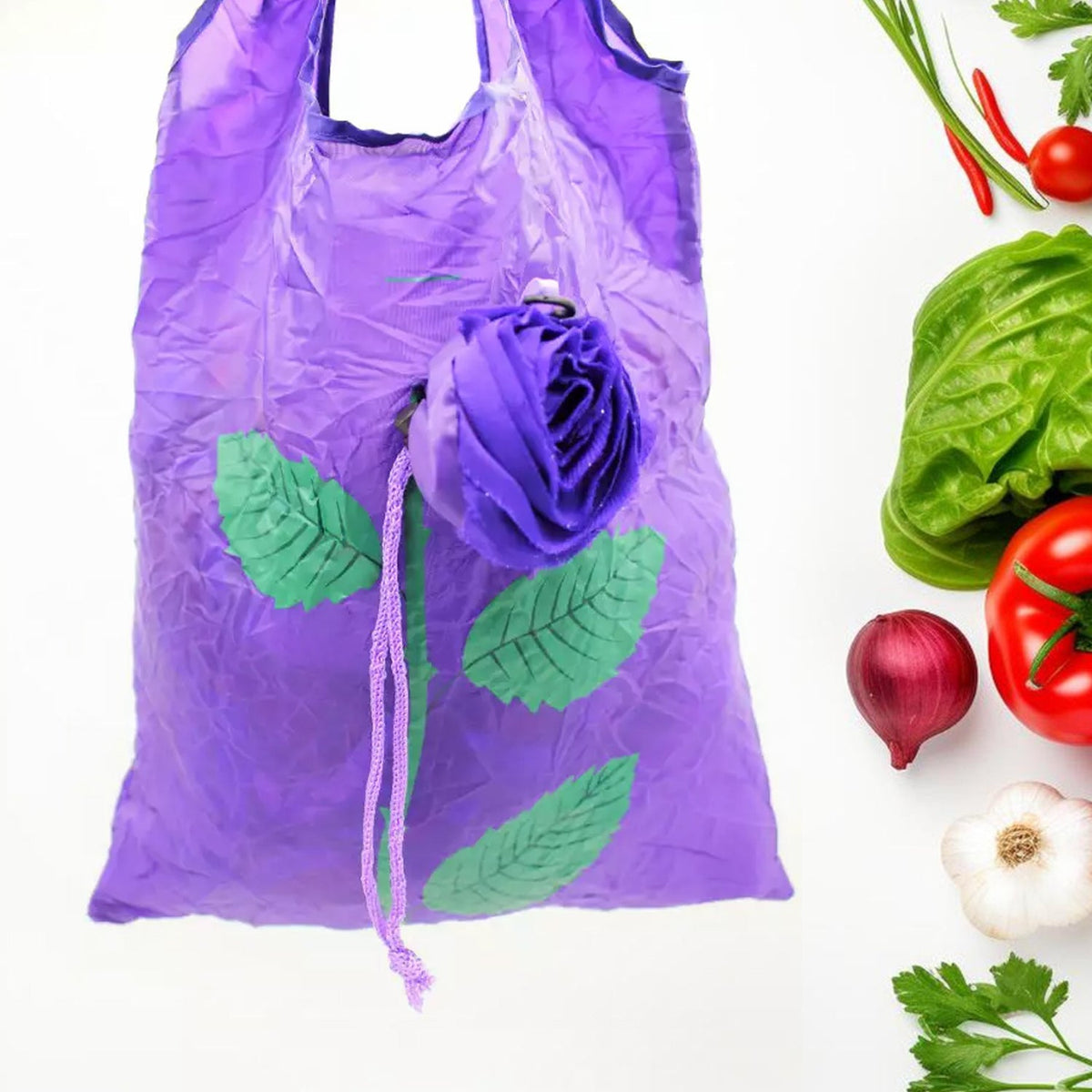 A purple foldable shopping bag with a rose design is shown with fresh vegetables in the background.