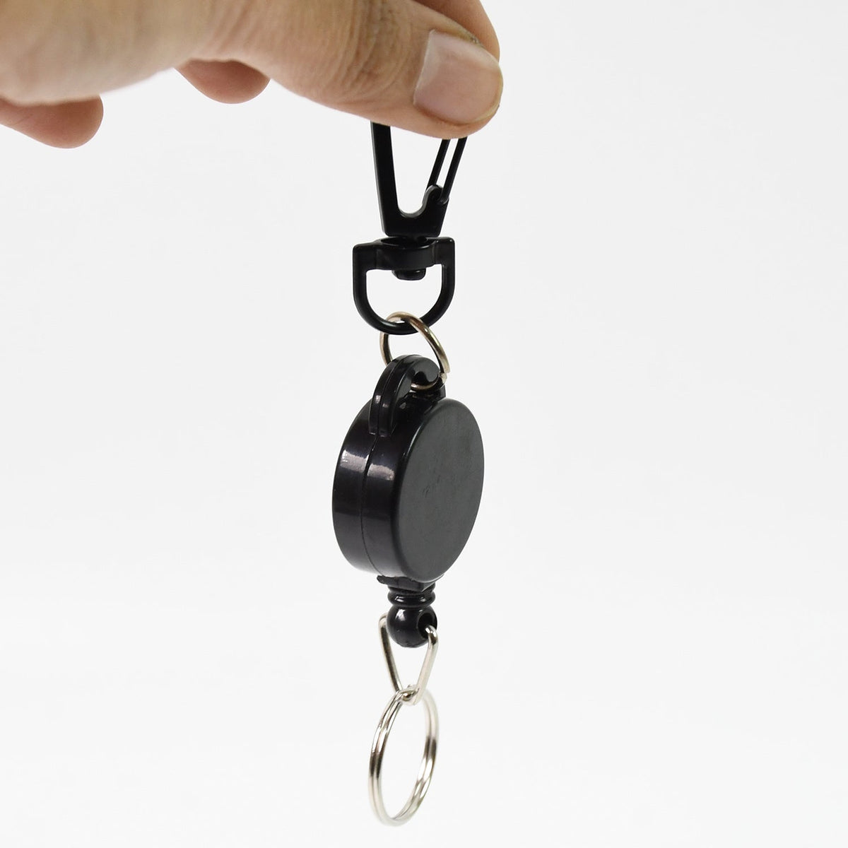 A hand holding a black retractable keychain with a biohazard symbol against a white background.