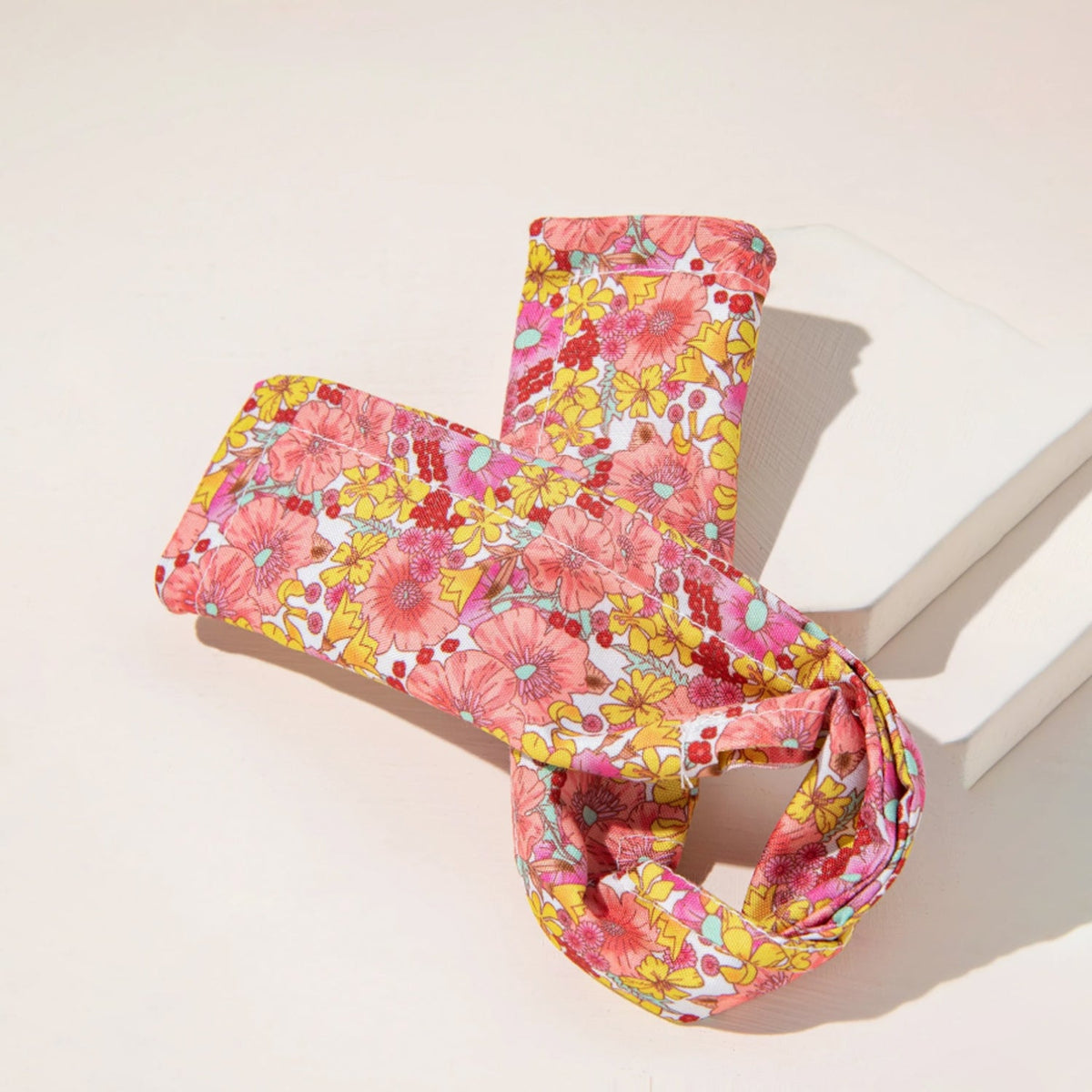 Pink and yellow knotted wire headband folded over white blocks on a light pink surface.