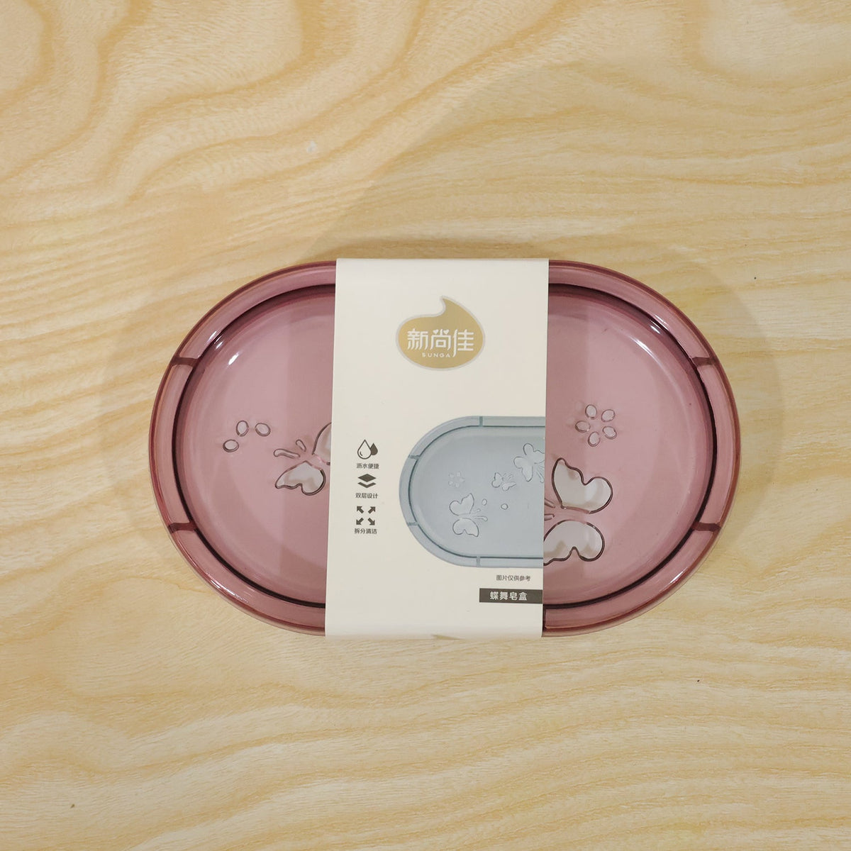 Pink butterfly-patterned soap case with a white product label on a light wooden surface.