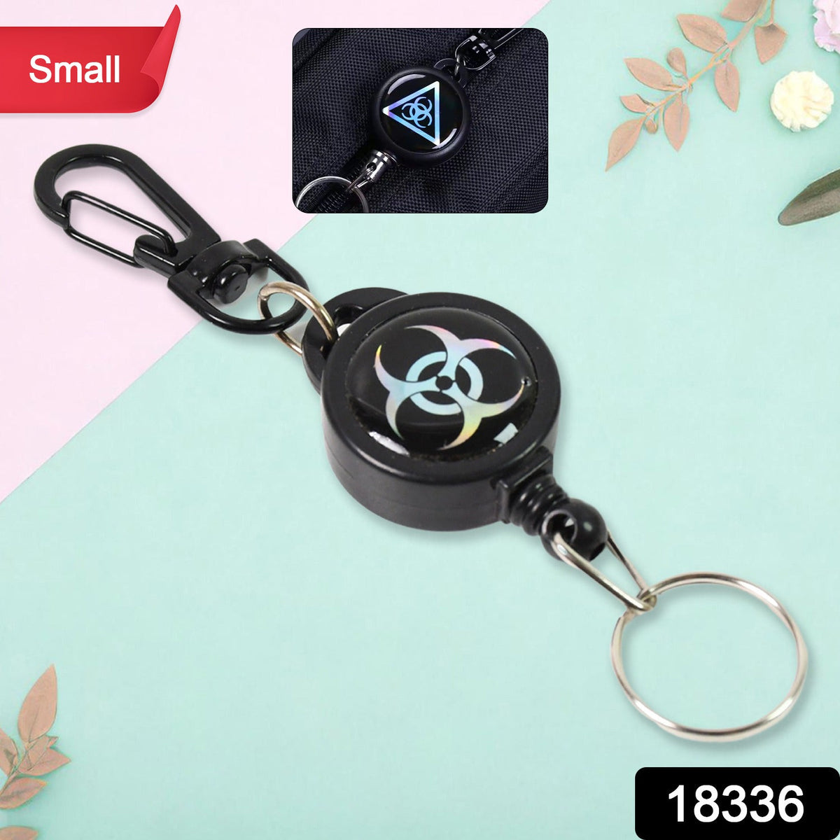 A black retractable keychain with a biohazard symbol on a light blue and pink background.