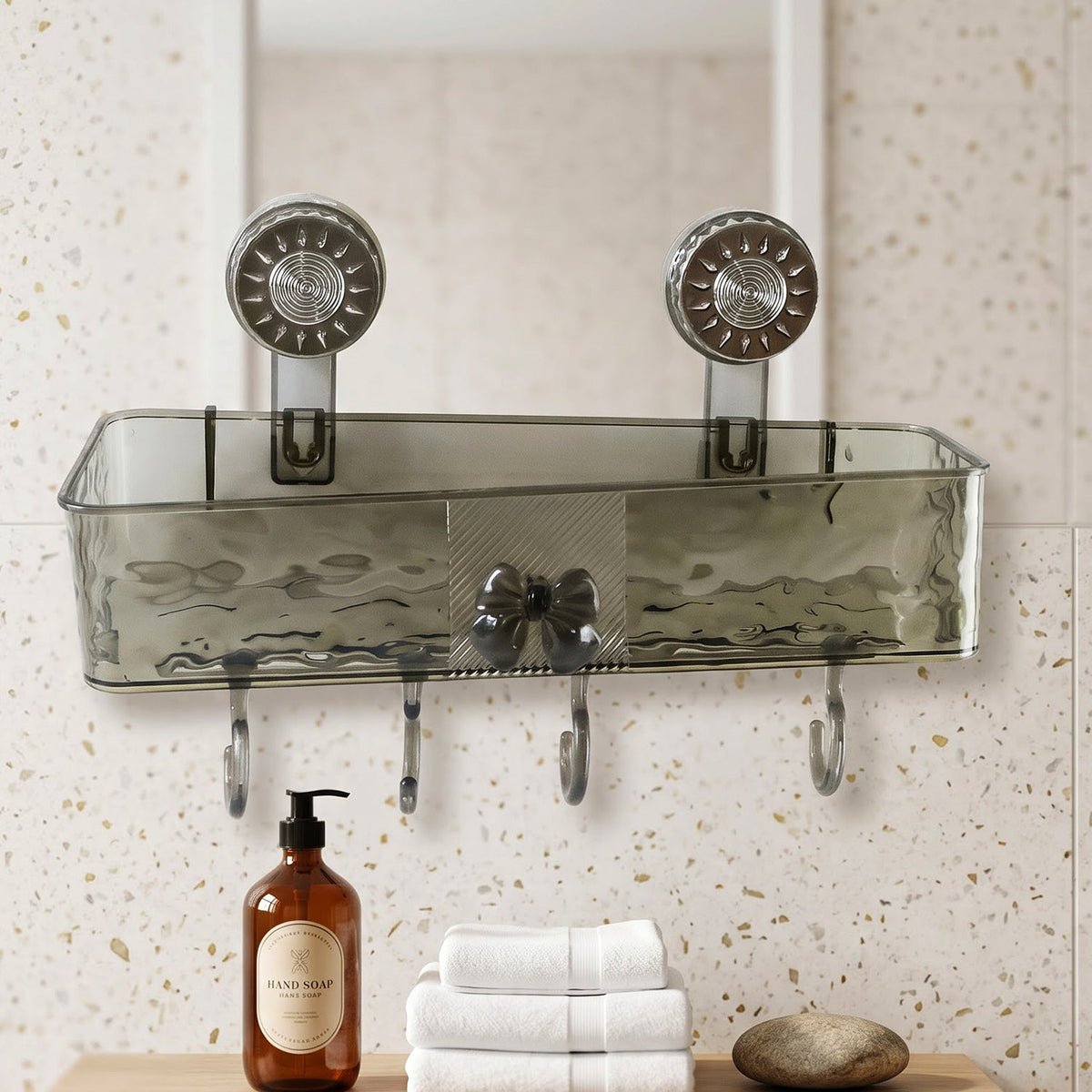 A clear grey plastic caddy with four hooks is mounted on a speckled wall above a wooden counter with soap and towels.