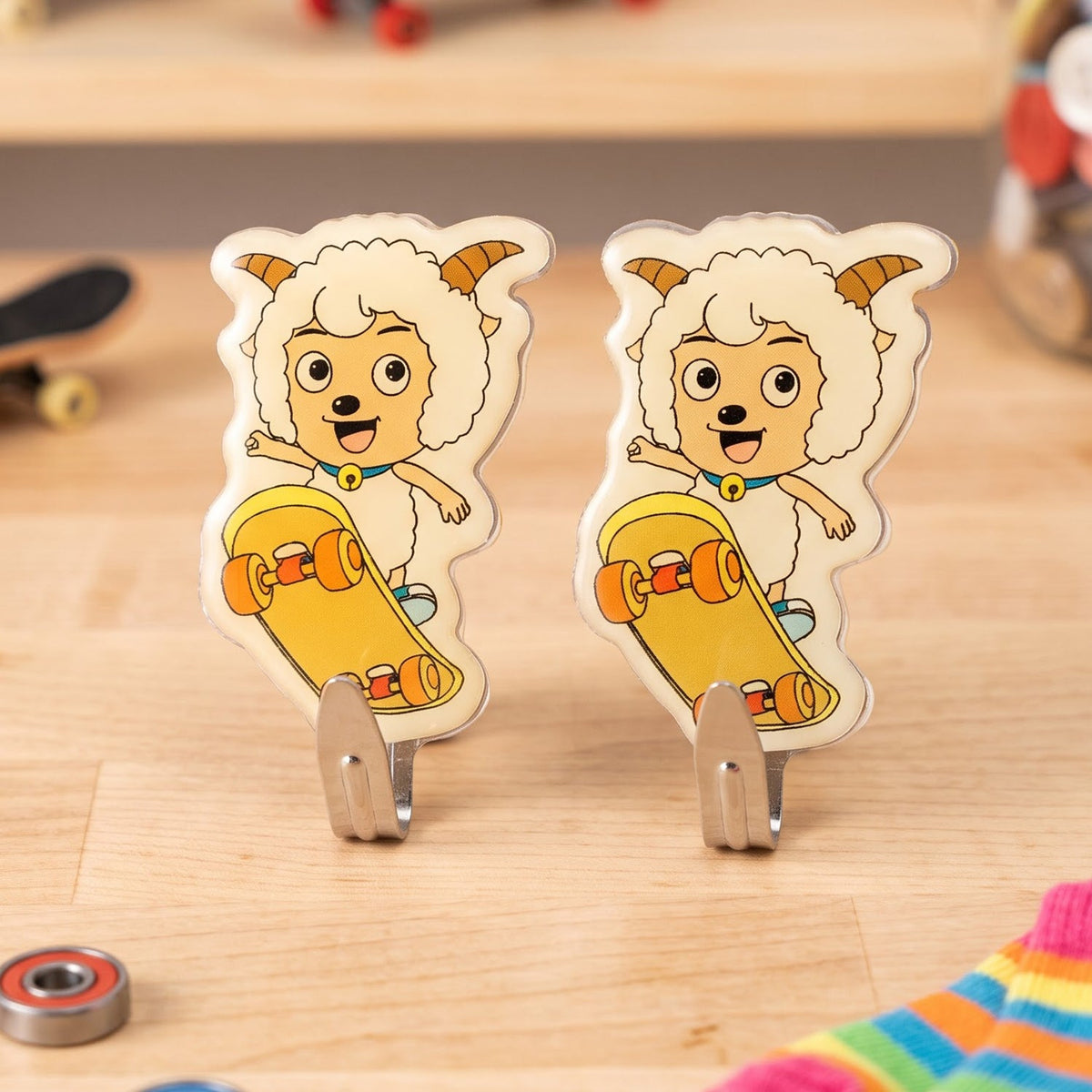 Two cartoon sheep on skateboards, acting as wall hooks, on a wooden surface with various small items.