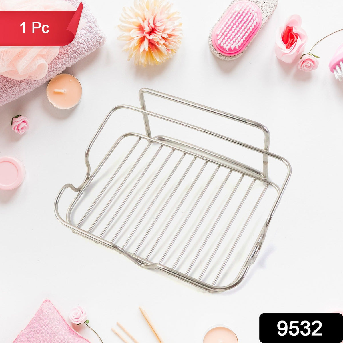 A stainless steel wire soap dish is centered on a white surface surrounded by pink bath accessories.