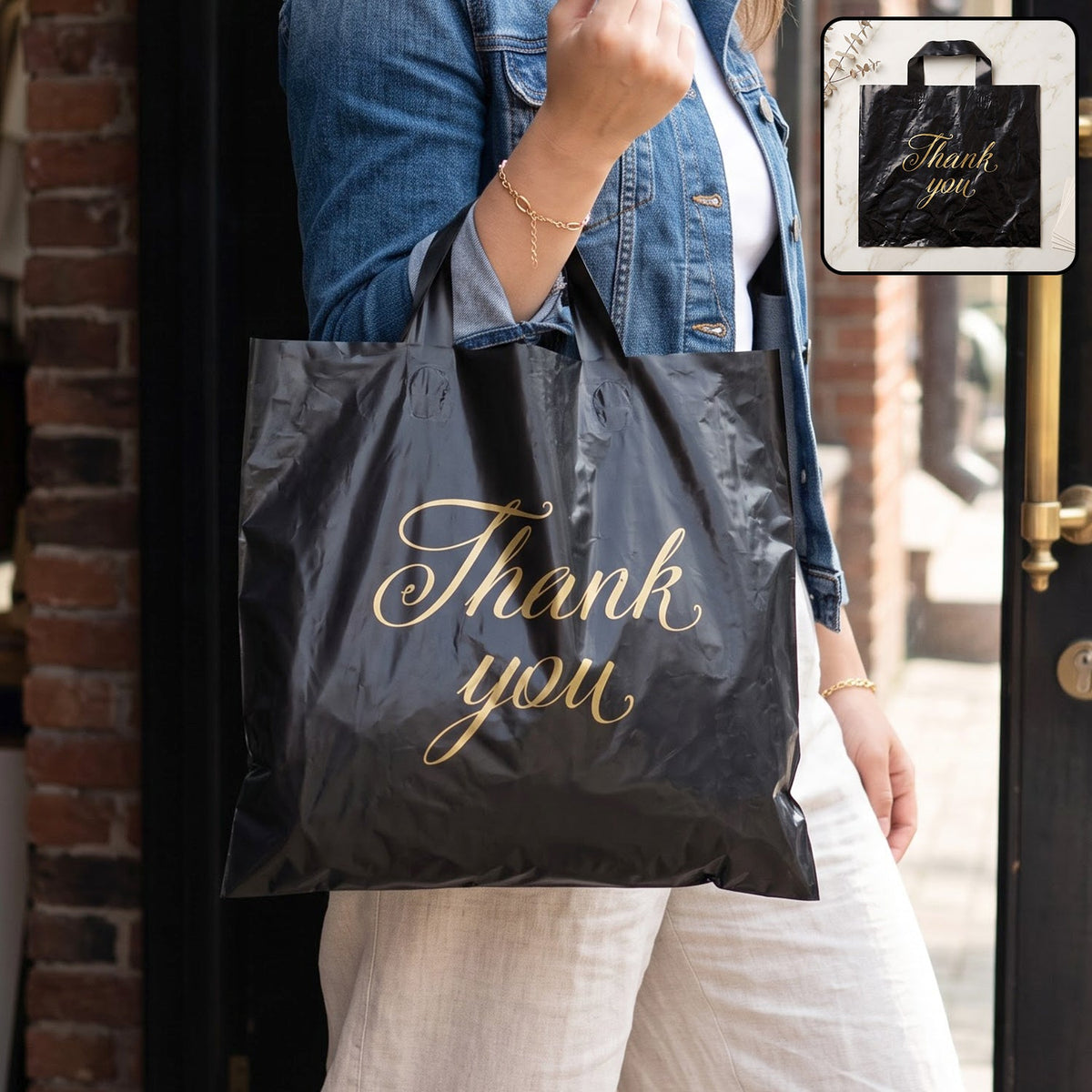 A person in a denim jacket holds a black plastic 'Thank You' bag with gold script, outdoors.