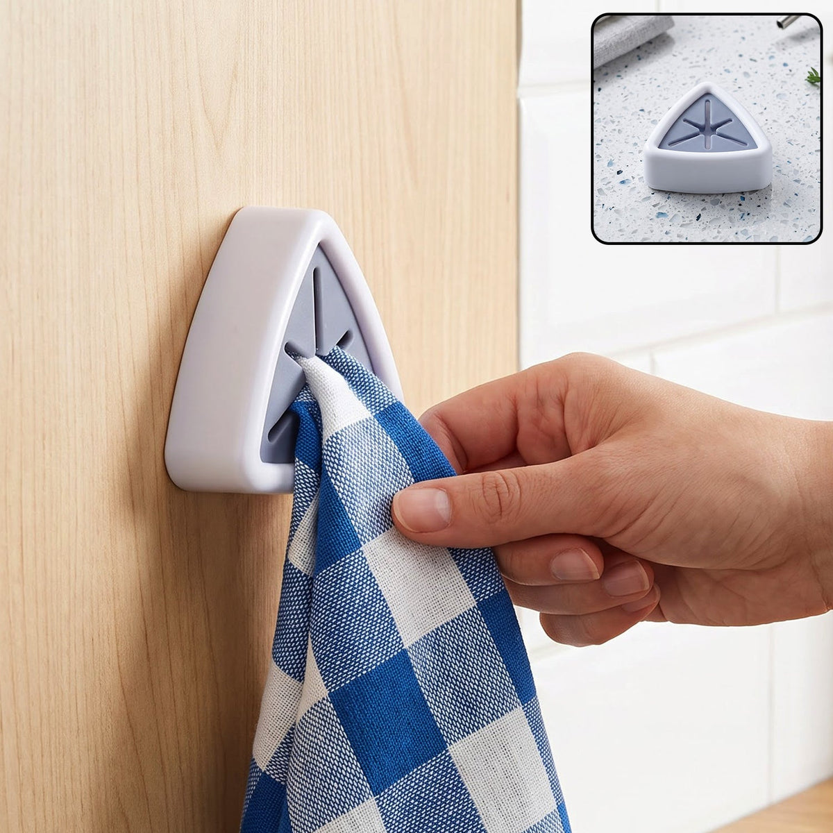 A hand inserts a blue and white checkered towel into a white and grey triangular wall-mounted towel holder on a light wood