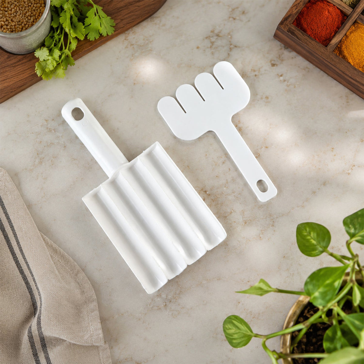 A white plastic meatball maker and a white plastic meatball shaper lie on a light-colored countertop with spices.