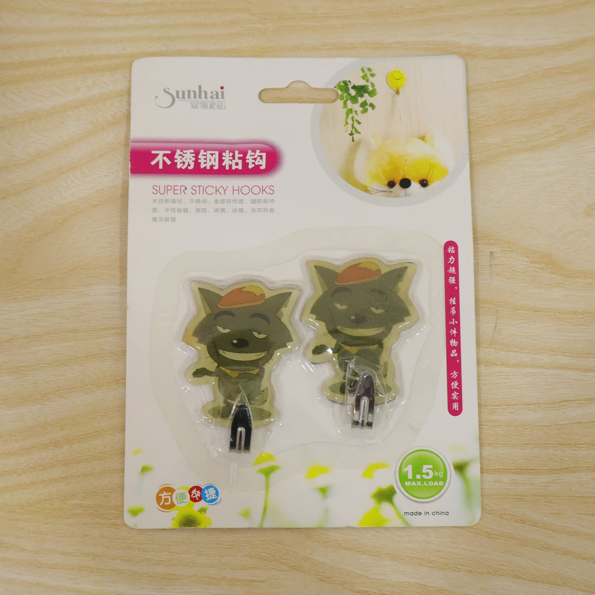 Packaging for two green cartoon goblin-like self-adhesive wall hooks, with text in Chinese and English.