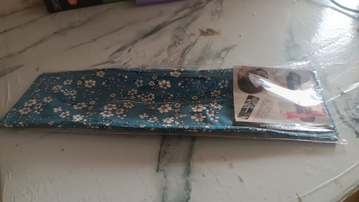 A knotted wire headband in clear plastic packaging on a patterned table.